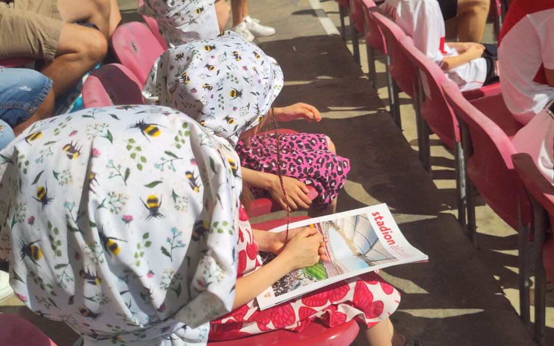 Kinder und Jugendliche sitzen im Fußball-Stadion